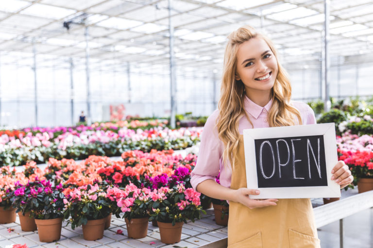Business owner holding an open sign in her new business
