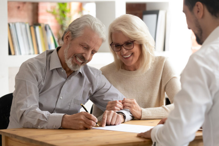 Two business owners signing papers to sell their business